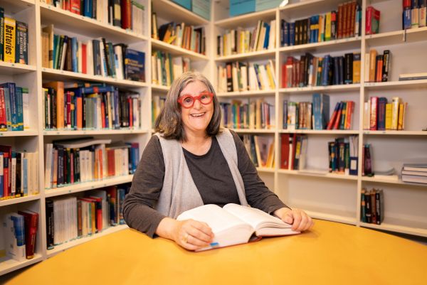 Bernadette Fulton smiling and sitting in front of bookshelves