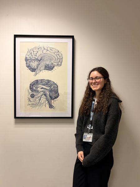 Person indoors standing next to a framed image on a wall