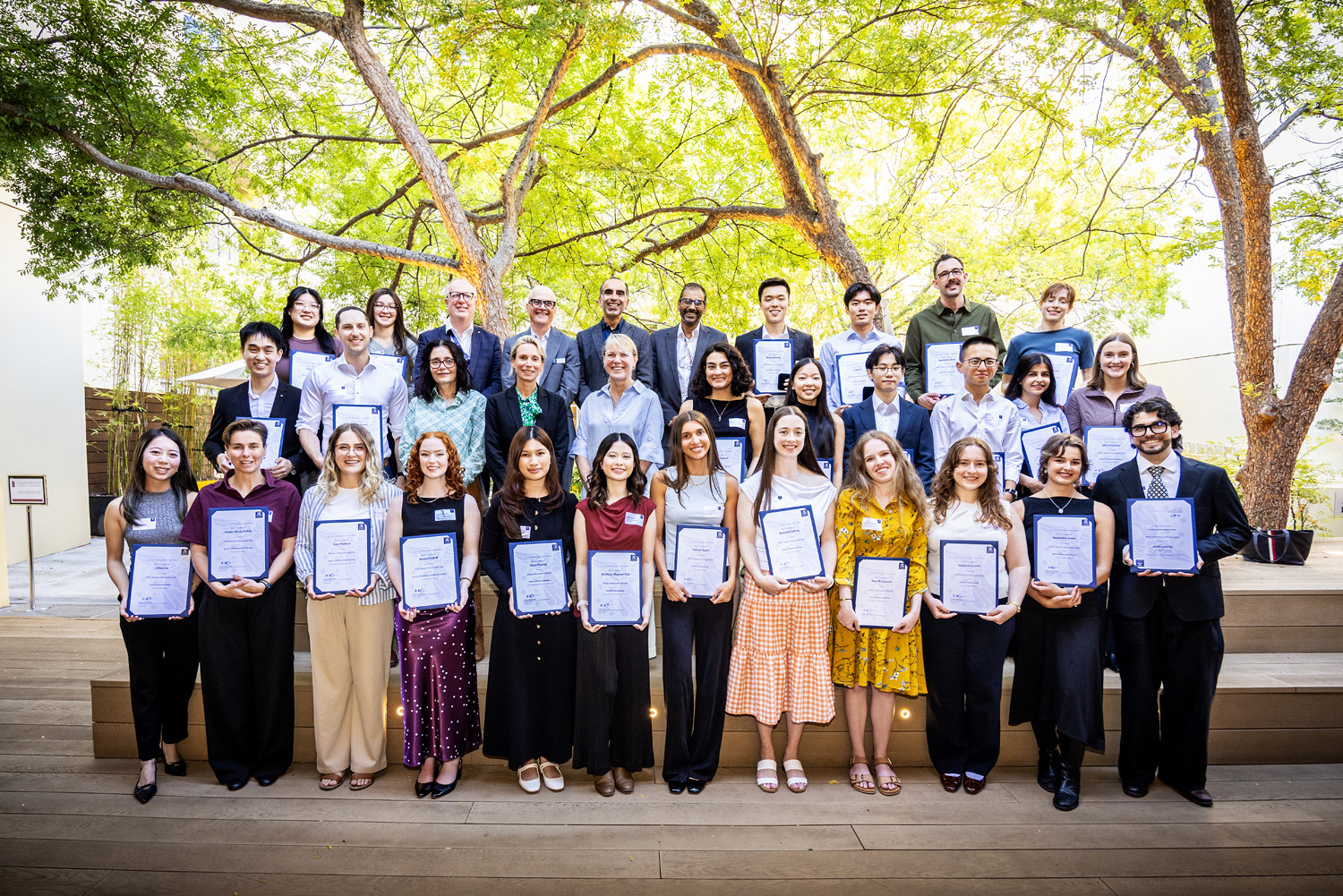 Group photo outdoors of award recipients holding their certificates