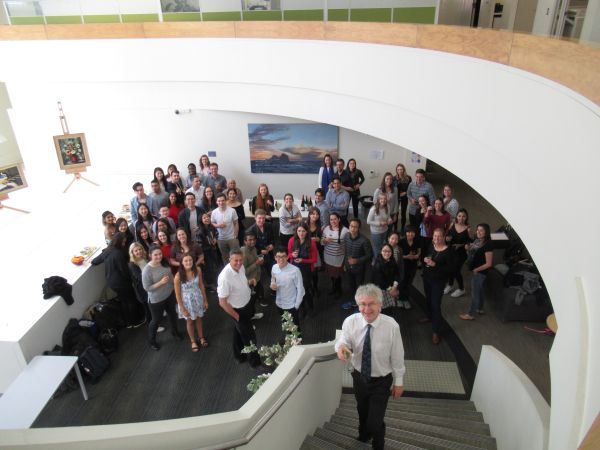 An overhead shot of a crowd of people in a foyer smiling up at the camera